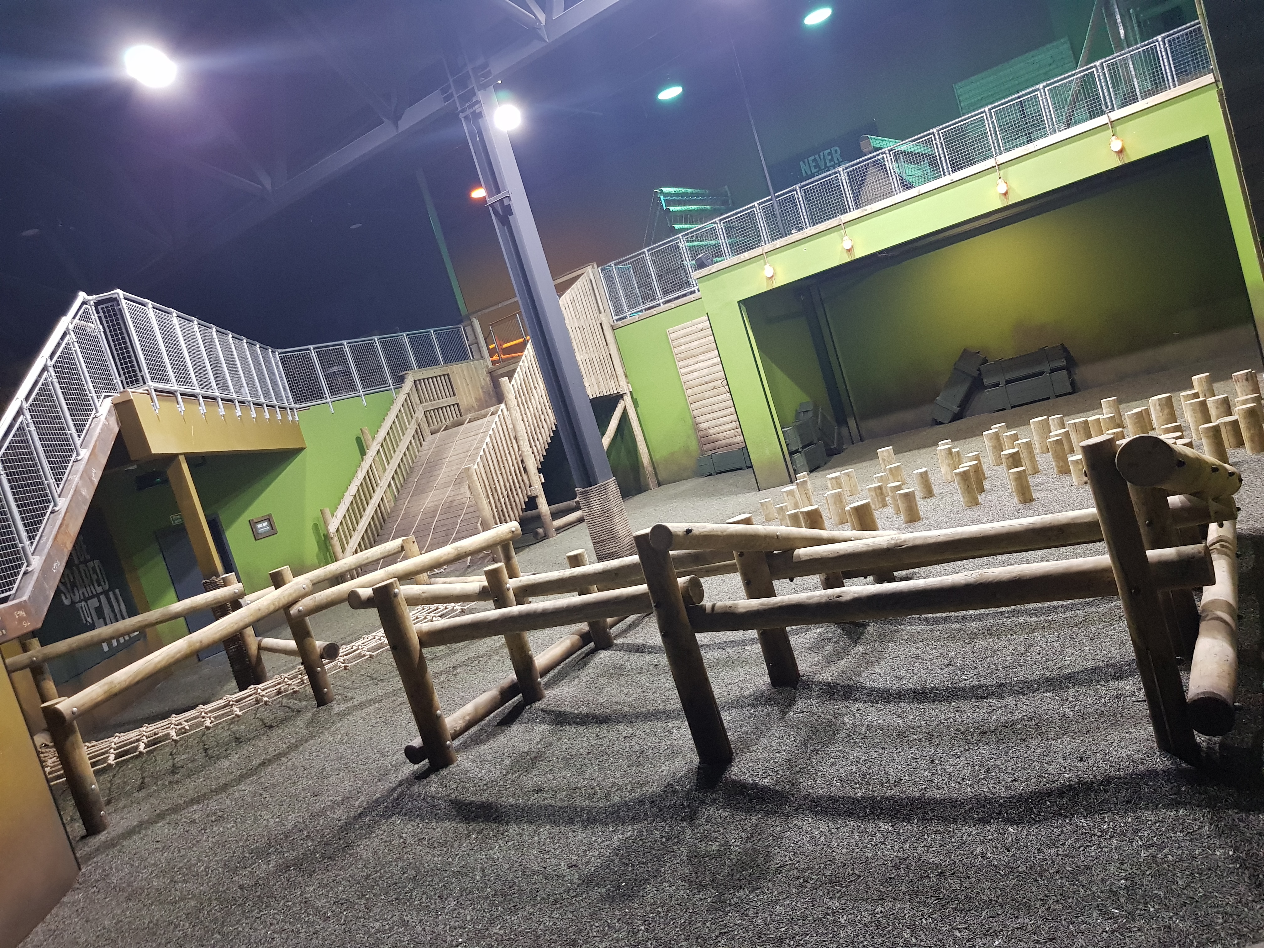 The Assault course at the Bear Grylls Adventure, Birmingham. Wooden stepping stones, poles for going under and over, a net to crawl under and a steep slope to climb up.