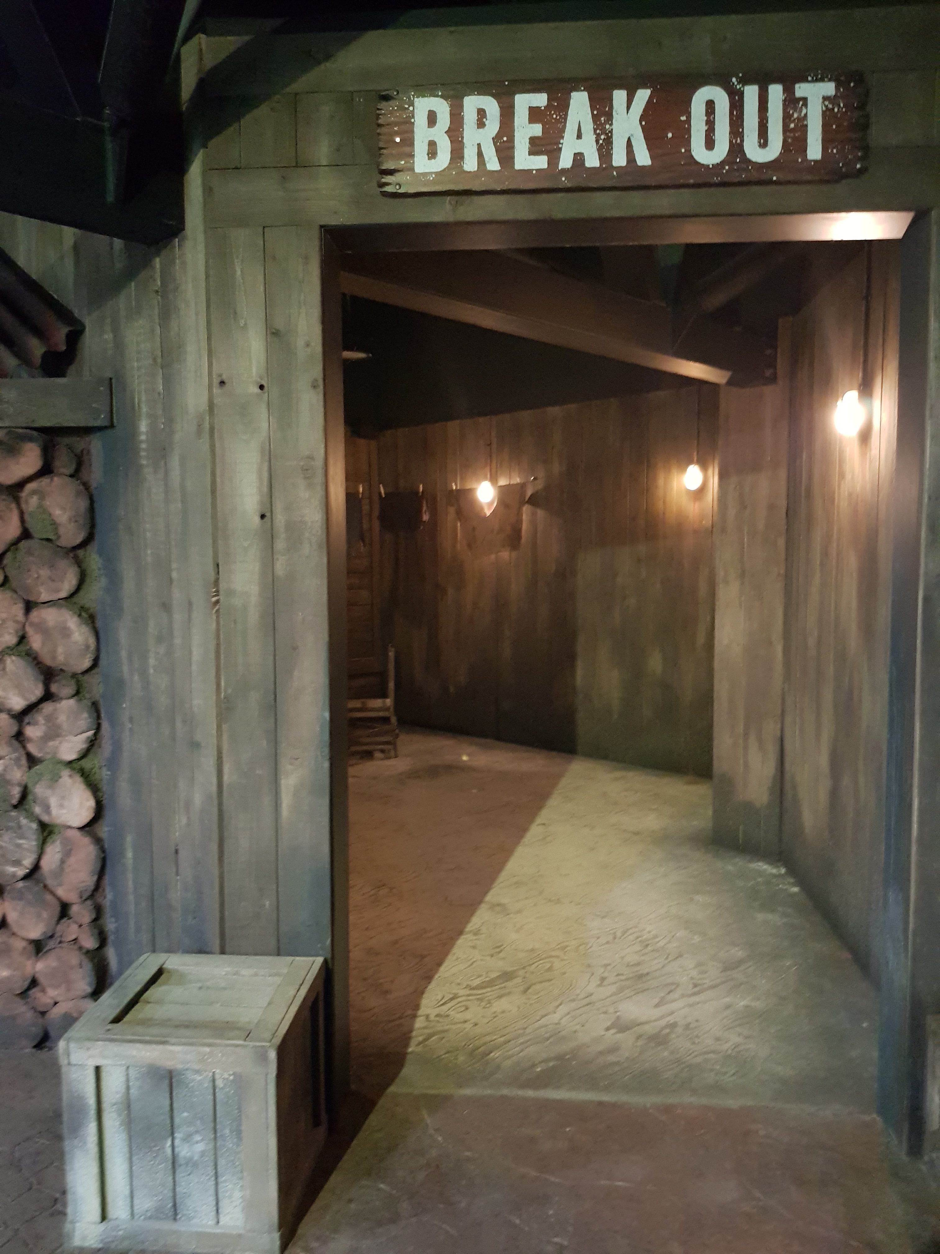 Entrance to the Break out escape room at the Bear Grylls Adventure. A Wooden door frame with BREAK OUT written above leading into a wooden corridor with a small wooden box outside