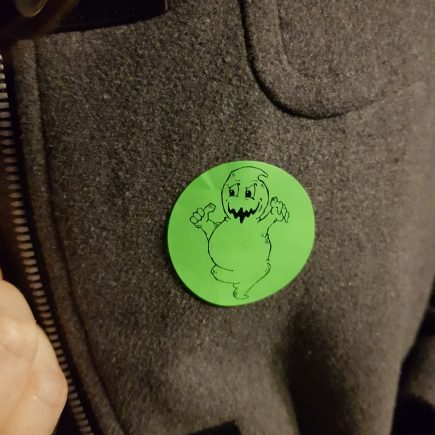 Green circular sticker with a cartoon ghost on it