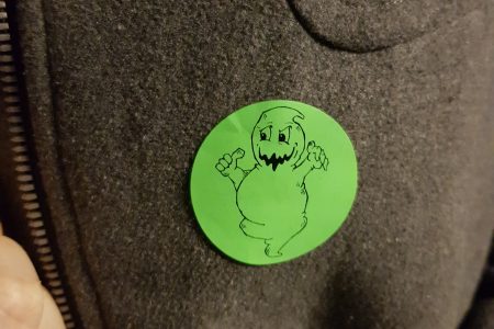 Green circular sticker with a cartoon ghost on it
