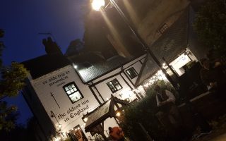 Outside of Ye Olde Trip to Jerusalem. A White pub with black roof. Outside sits Gary the Co-owner of the Original Nottingham Ghost Walk