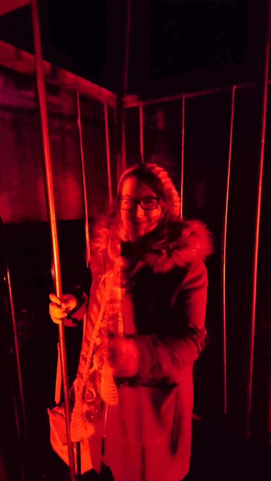 Night time photo of a young girl in a cage smiling with red lighting