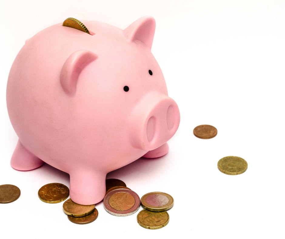 a pink piggy bank with coins scattered around it