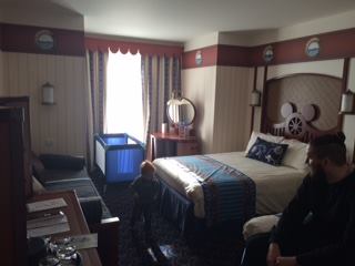 Inside the Newport Bay Club hotel room. A nautical themed room in blue, brown and cream with a ships steering wheel with mouse ears on the bed headboard