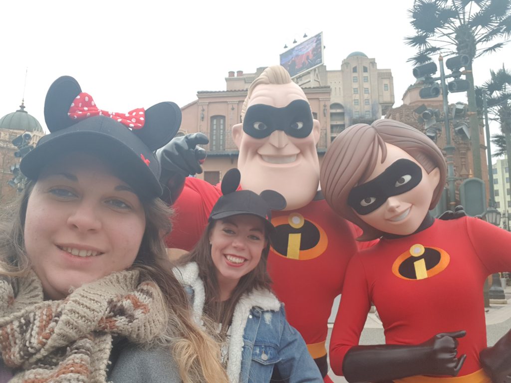 2 girls with Mickey mouse ear hats taking a selfie with Mr and Mrs incredible characters
