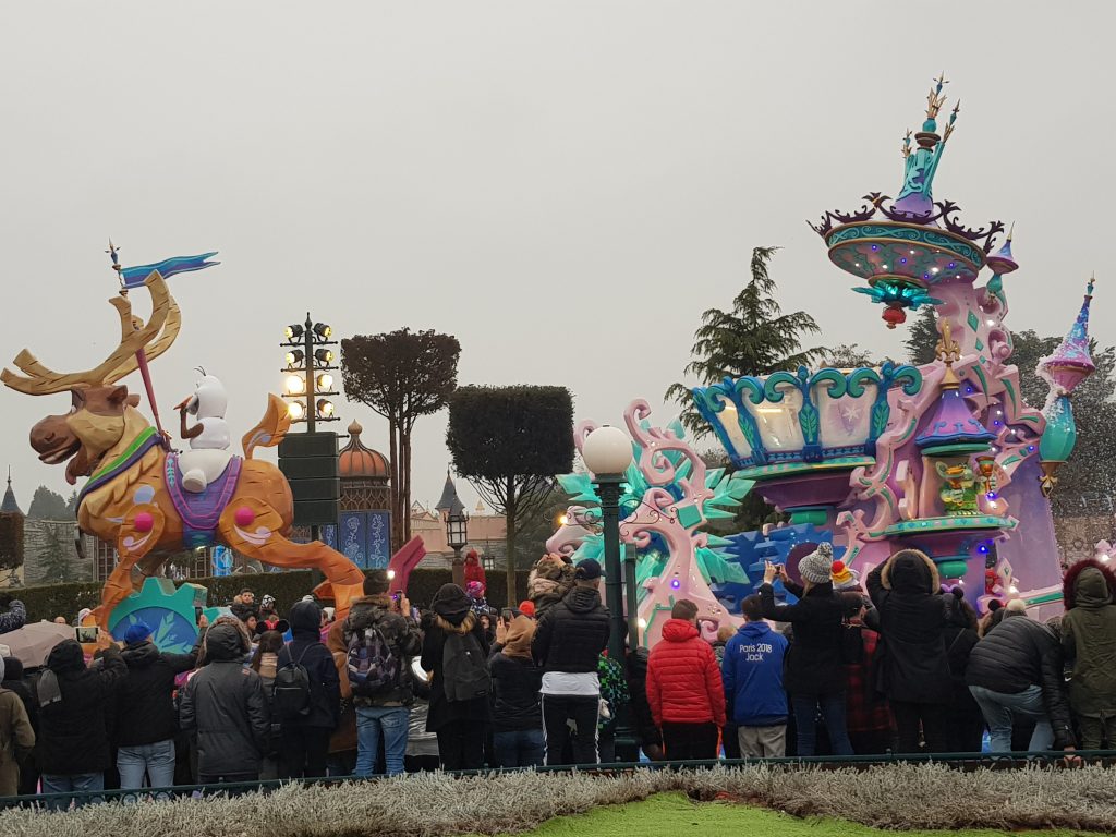 Parade floats from Stars on Parade at Disneyland Paris. Olaf sits on a giant Sven float while a pink and blue ice sledge is pulled behind