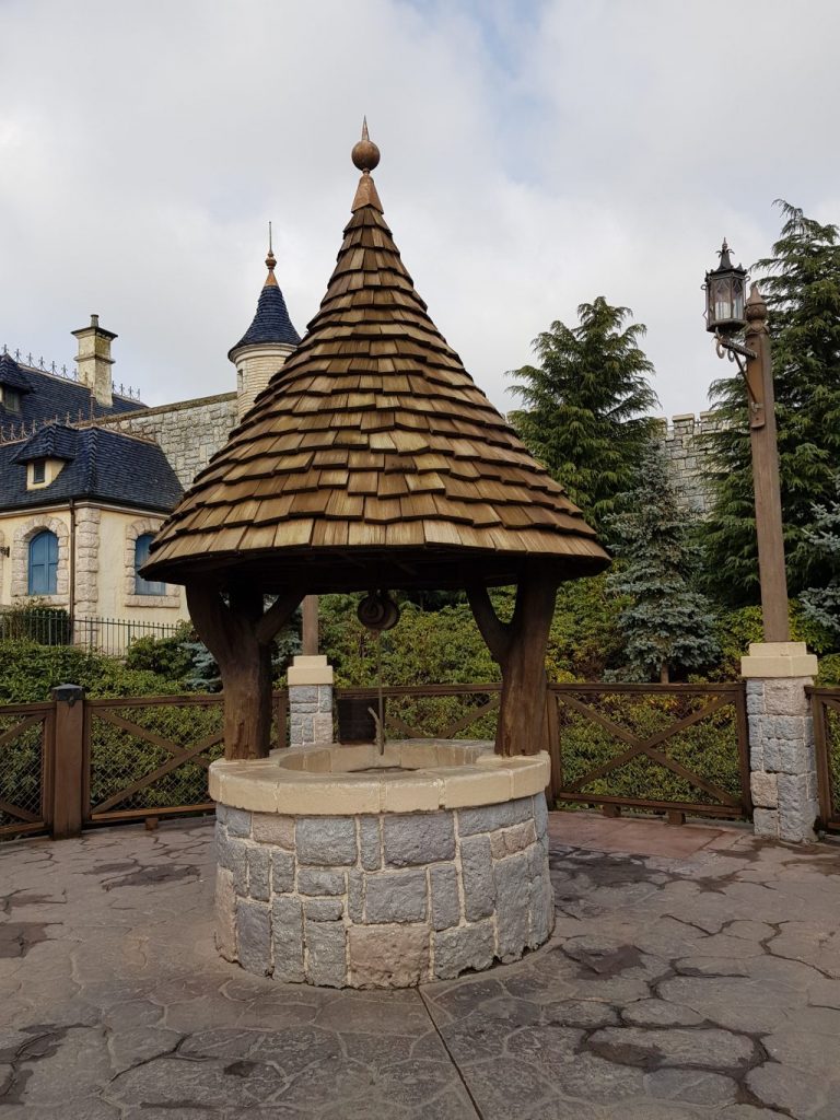 A grey stone wishing well with brown wooden cone roof like the one seen in Snow White