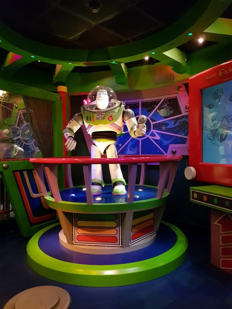 Animated Buzz Light year statue on a platform behind red bars found inside the Buzz Lightyear Laser Blast ride