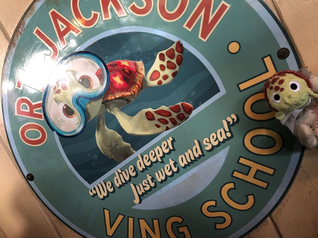 A sign at Crush's Coaster with a picture of Squirt wearing goggles. The sign says Port Jackson Diving School