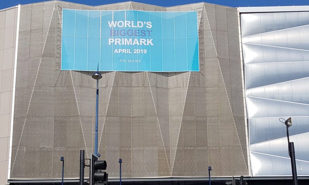 Outside shot of the World's largest Primark building. A grey angular building with a blue sign with white writing on it saying world's biggest Primark.