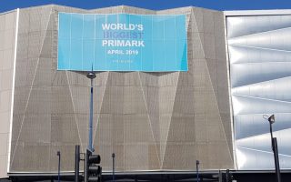 Outside shot of the World's largest Primark building. A grey angular building with a blue sign with white writing on it saying world's biggest Primark.
