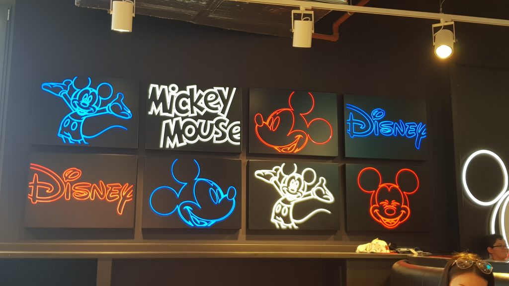 Black squares with neon red, white and blue images of Mickey Mouse and Disney logo found in the Disney cafe
