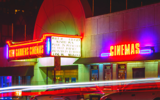 Old fashioned style cinema with retro neon signs showing wanderlust movies
