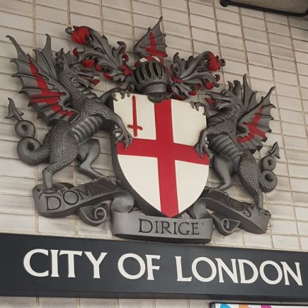 Sign saying City of London with an English flag on a shield being held by two dragons. One of the clues in Hidden City London