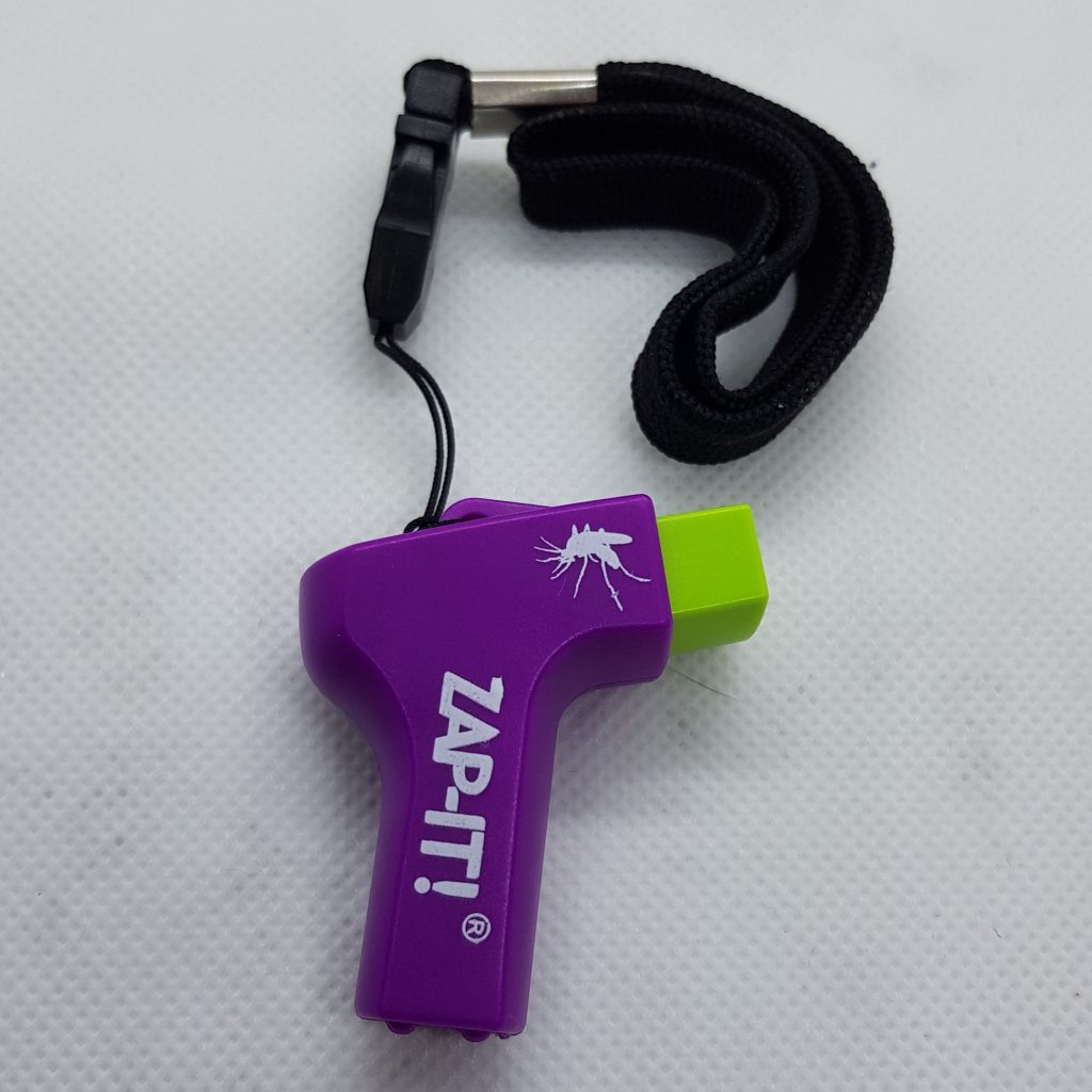 A purple gun shaped device with a green button, white writing saying Zap-it! and a black string loop for attaching the device to bags ect.