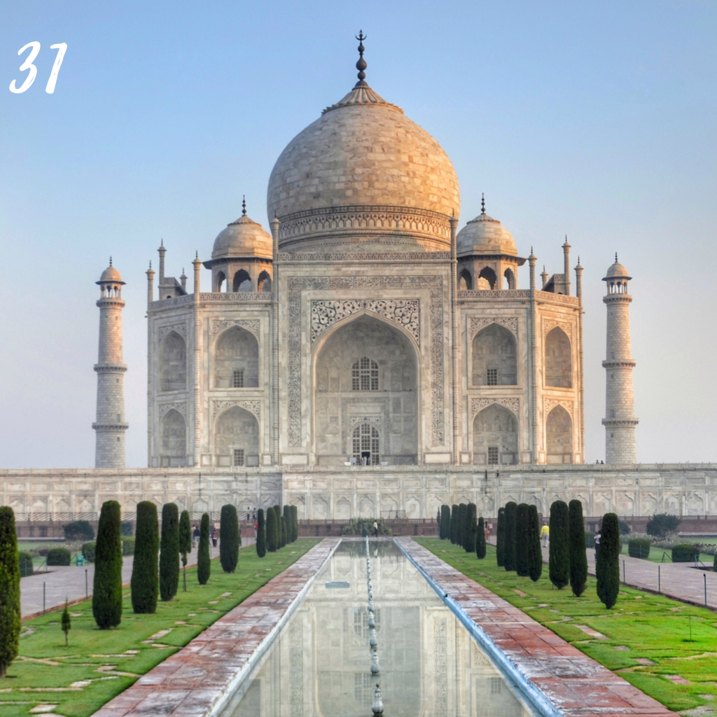 Number 31. The Taj Mahal temple with high archways, large rounded domes and long reflection pool in front.