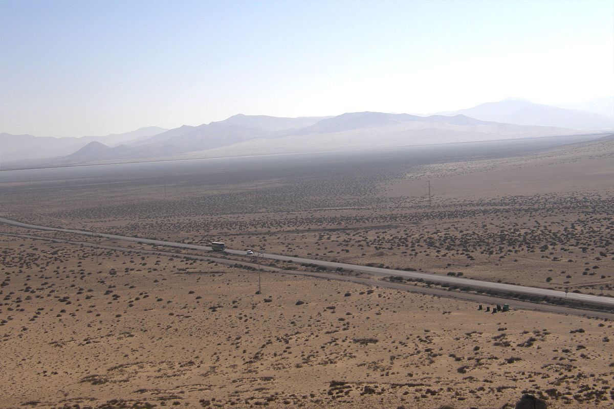 A stretch of road surrounded by dessert and mountains