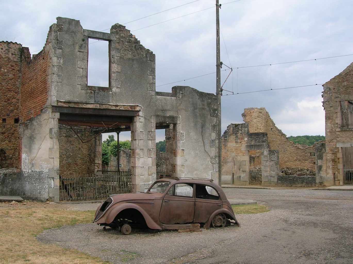 A burned out car in front of the ruins of a building