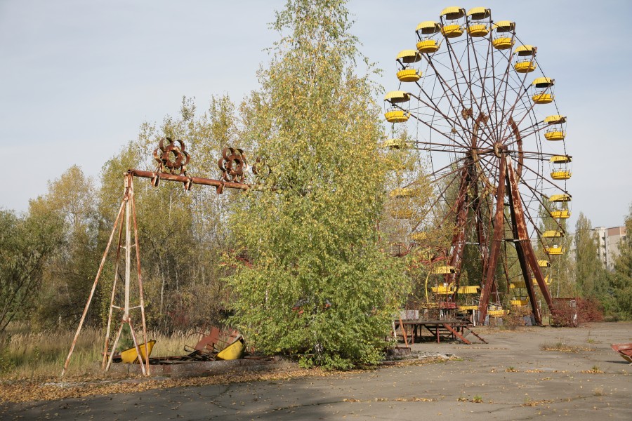 An abandoned theme park with broken swings and a Ferris Wheel